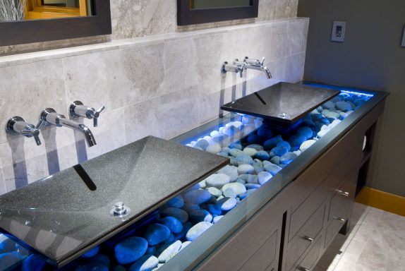 Moderne Waschbecken in einem stilvollen Badezimmer mit blauen Lichtern und Steindekor.