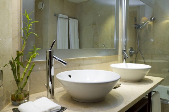 Elegantes Badezimmer mit zwei Waschbecken, einer Pflanze und modernem Design.