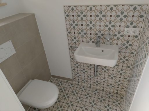 Gäste-WC mit Großformatfliesen und dekorativen Fliesen im Waschtischbereich