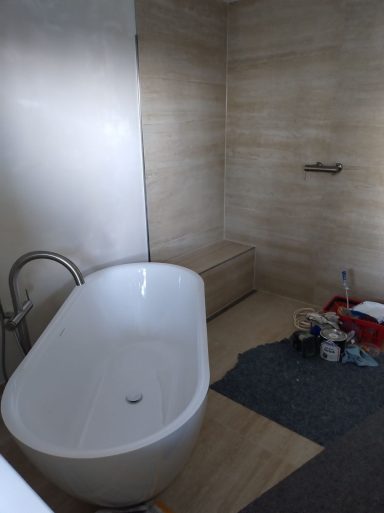 Barrierefreies Badezimmer mit Dusche und Sitzbank sowie Großformatfliesen (120&nbsp;×&nbsp;60) und Badewanne
