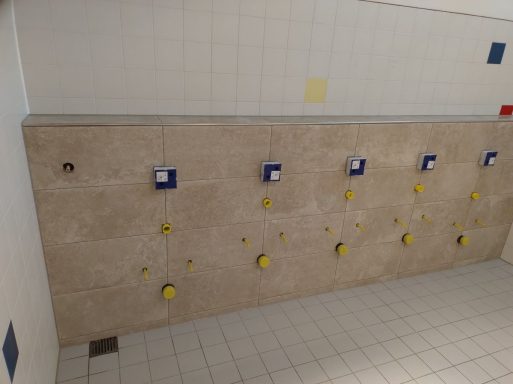 Geflieste Wand mit Urinalen im Herren-WC einer Schule