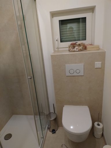 Kleines Badezimmer mit WC und Dusche – Fliesen in Marmoroptik und weiße Wände in Q4-Spachtelqualität