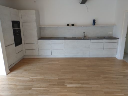 Moderne Küche mit hellen Schränken, einem Waschbecken und Fertigparkett.