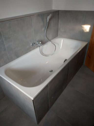 Badewannenbereich mit grauen Fliesen in Marmoroptik im Badezimmer