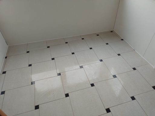 Bodenfliesen in Marmoroptik mit schwarzen Dekorfliesen in den Ecken