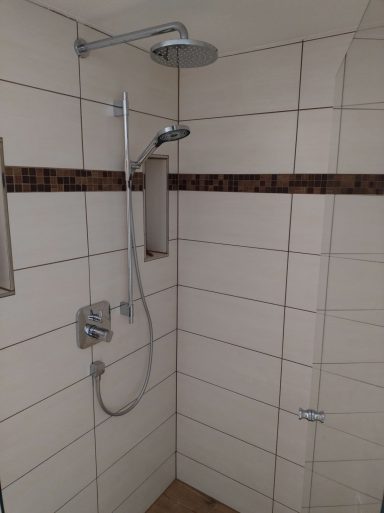 Dusche mit braunem Mosaikstreifen, dunklen Fugen und Wandnische sowie weißen Fliesen