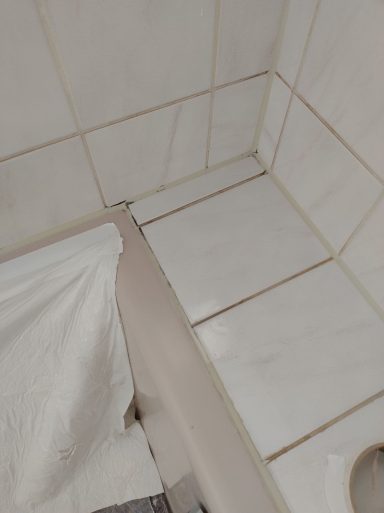 Verschmutzte Zementfugen und verschimmelte Silikonfugen im Badewannenbereich vor der Fugensanierung