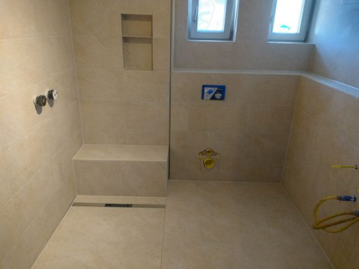 Dusche mit Sitzbank und Wandnische, helle Fliesen in Marmoroptik