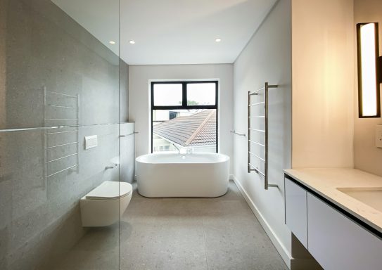 Modernes Badezimmer mit freistehender Badewanne und Fensterblick. Helle, minimalistische Ausstattung.