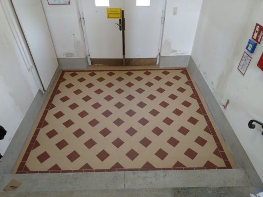 Rekonstruktion eines historischen Fliesenbodens mit zweifarbigen Fliesen in einer Schule