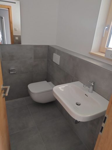 Badezimmer mit grauen Fliesen und weißen Wänden in Q4-Spachtelqualität