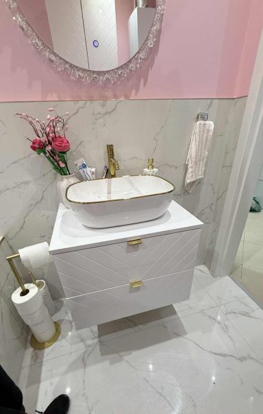 Waschtisch mit Spiegel und hellen Fliesen in Marmoroptik im modern renovierten Badezimmer