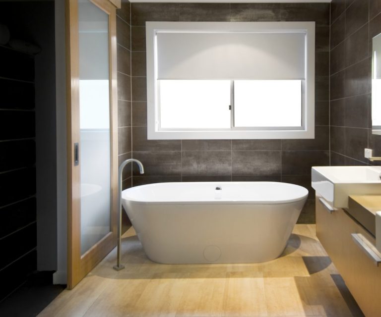 Modernes Badezimmer mit freistehender Badewanne, Holzoptikfliesen und großer Fensterfront.