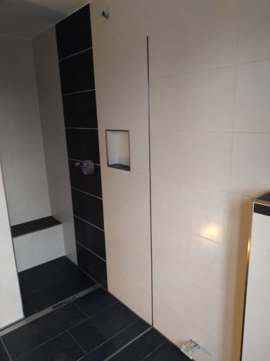 Dusche mit Sitzbank und Wandnische – weiße Wandfliesen mit schwarzen Akzenten sowie schwarzer Boden