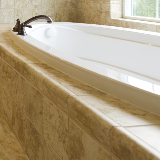 Helle Badewanne aus weißem Material mit elegantem gebogenen Wasserhahn und Fliesenboden.